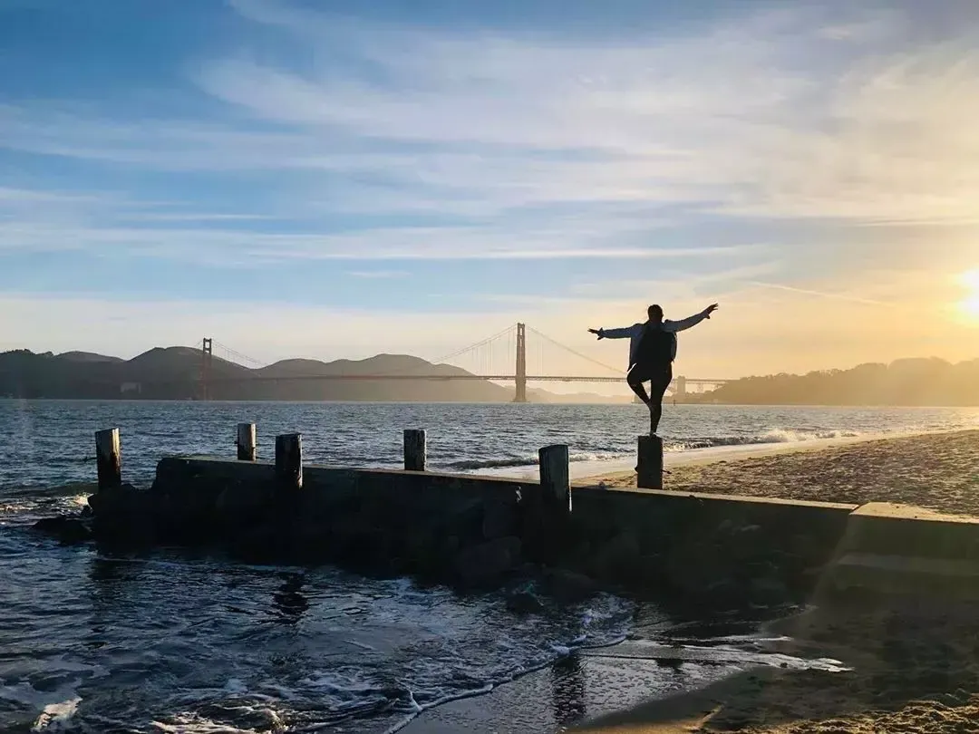 woman stands on A pier in San Francisco's Marina neighborhood, looking out at the Golden Gate Bridge.