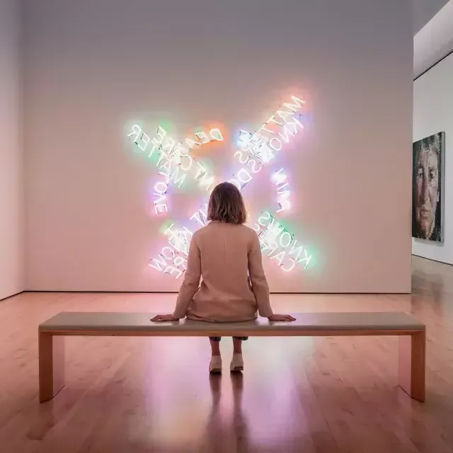 Eine Frau sitzt auf einer Bank und betrachtet ein Stück zeitgenössischer Lichtkunst im SF MOMA in San Francisco.